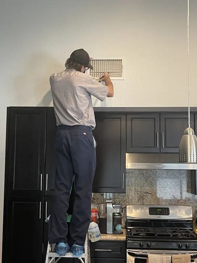 Technician inspecting an air vent during HVAC service in North Lynnwood